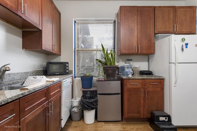 kitchen featuring light stone countertops, sink, white appliances, and light wood-type flooring