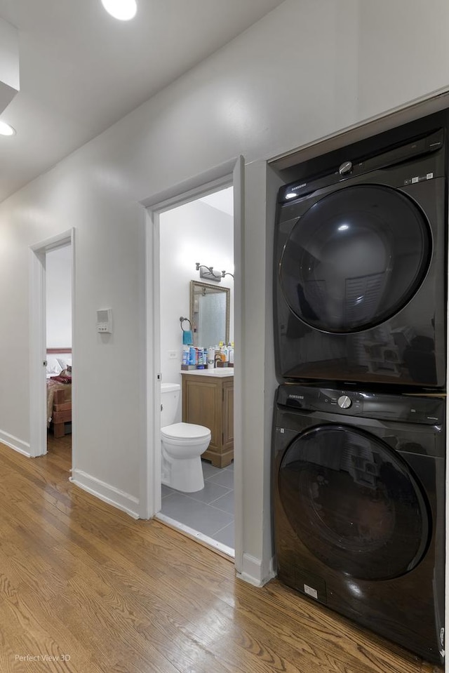 washroom with stacked washer / dryer and hardwood / wood-style flooring