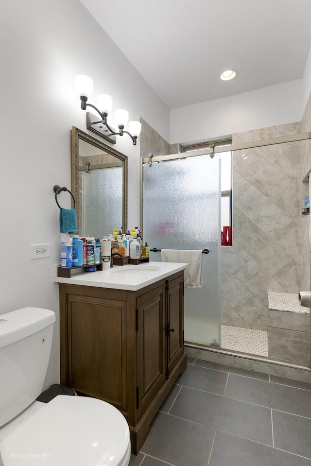 bathroom featuring tile patterned flooring, vanity, toilet, and walk in shower