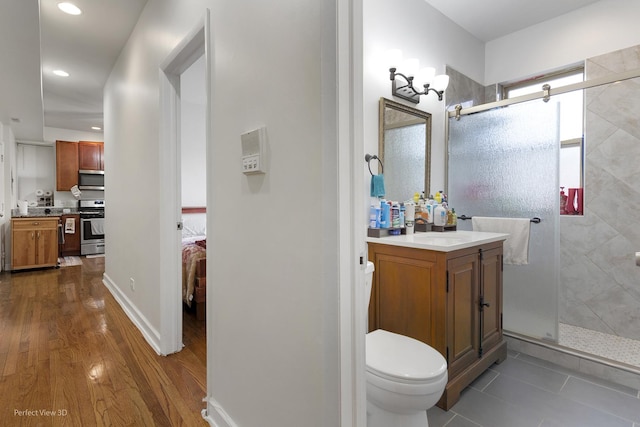 bathroom with a shower with door, vanity, hardwood / wood-style flooring, and toilet