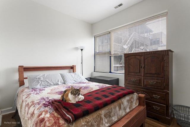 bedroom with multiple windows and dark hardwood / wood-style floors