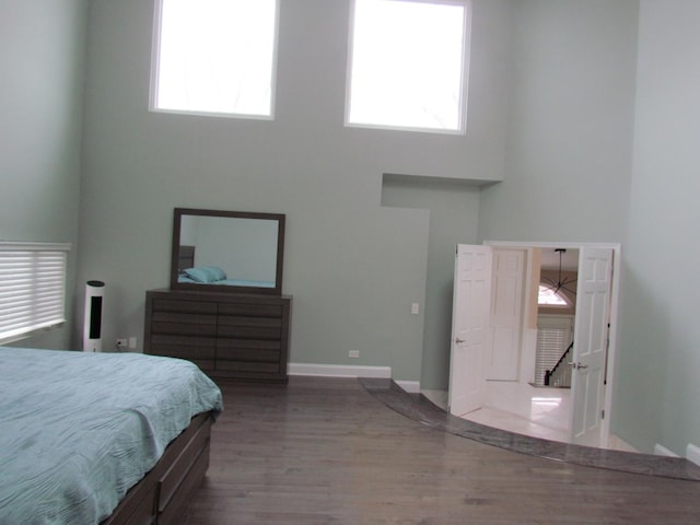 bedroom featuring wood-type flooring and a high ceiling