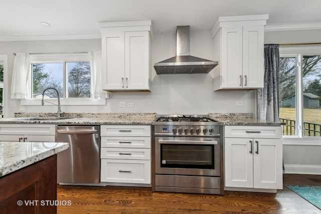 kitchen featuring stainless steel appliances, white cabinetry, sink, and wall chimney range hood