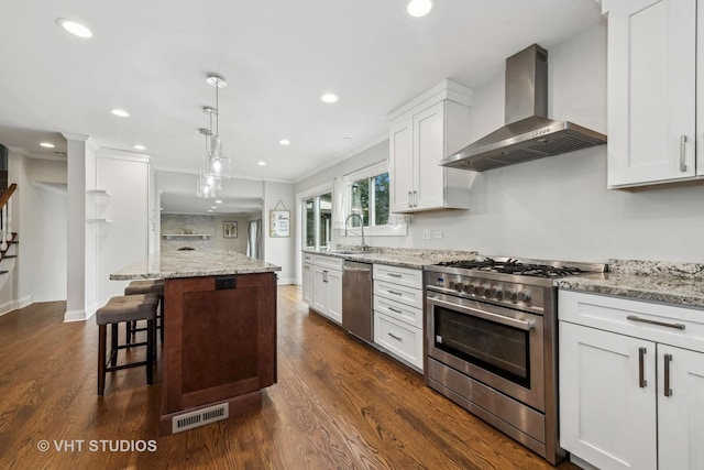 kitchen featuring stainless steel appliances, a kitchen island, white cabinets, and wall chimney exhaust hood