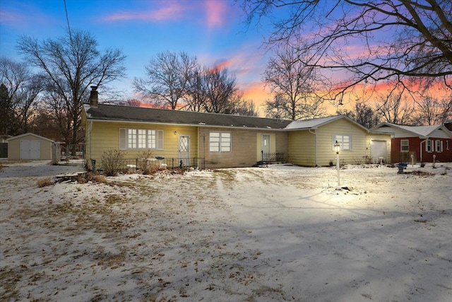 ranch-style home featuring a storage shed, a chimney, an outdoor structure, and a garage