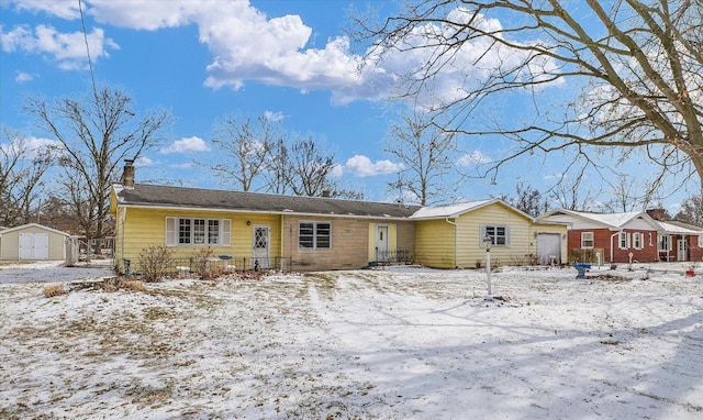 single story home featuring a garage, an outdoor structure, a chimney, and a storage shed