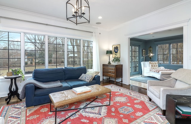 living room with crown molding, wood-type flooring, and an inviting chandelier