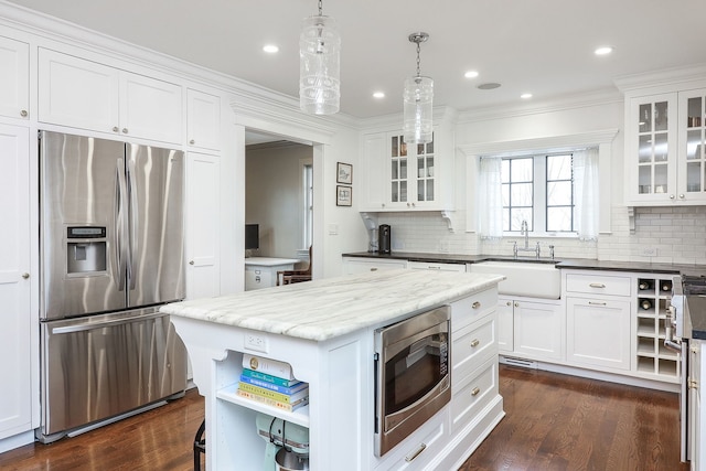 kitchen featuring white cabinetry, sink, decorative light fixtures, and stainless steel appliances