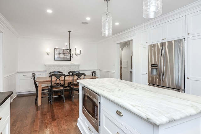 kitchen with stainless steel appliances, white cabinetry, and decorative light fixtures