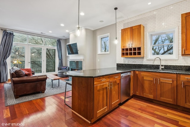 kitchen featuring dishwasher, hardwood / wood-style floors, decorative backsplash, decorative light fixtures, and dark stone counters