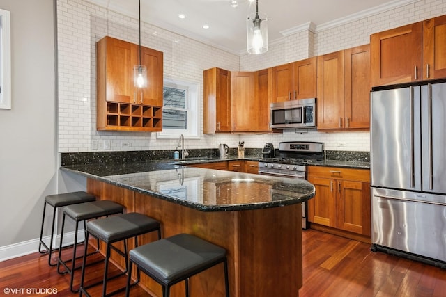 kitchen featuring hanging light fixtures, a kitchen bar, dark stone counters, and appliances with stainless steel finishes