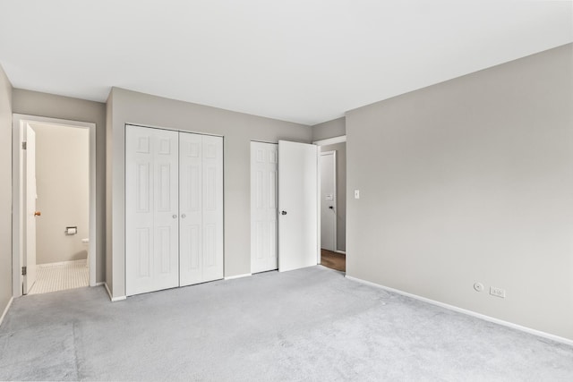 unfurnished bedroom with multiple closets, connected bathroom, and light colored carpet