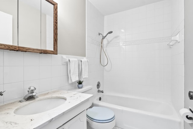 full bathroom with vanity, toilet, tiled shower / bath combo, and tile walls