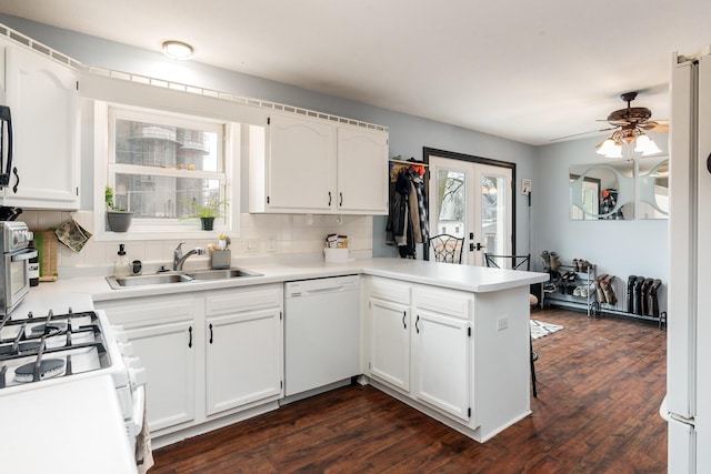 kitchen with white cabinetry, sink, white appliances, and kitchen peninsula