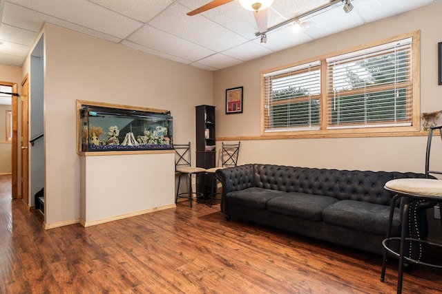 living room featuring hardwood / wood-style flooring, a paneled ceiling, and ceiling fan