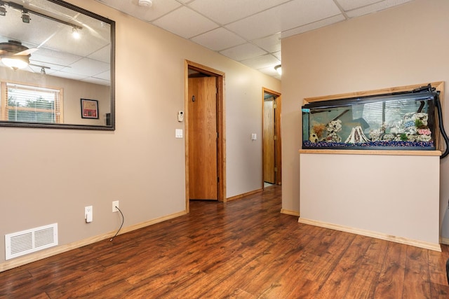 spare room with dark hardwood / wood-style floors and a drop ceiling