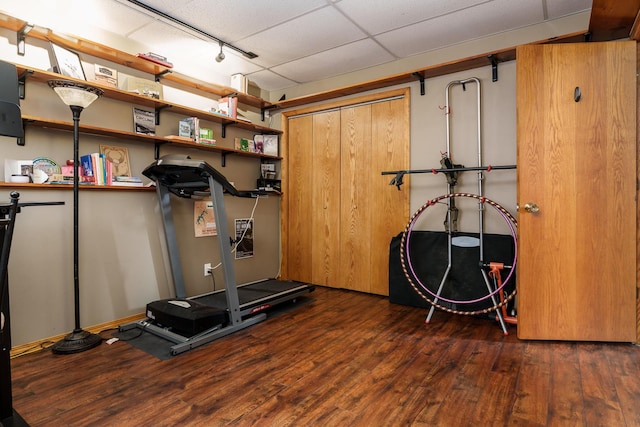 workout area featuring dark hardwood / wood-style floors, rail lighting, and a drop ceiling