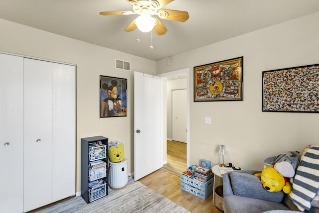 living area with ceiling fan and light hardwood / wood-style flooring