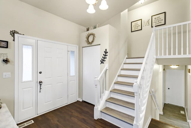 entryway with an inviting chandelier and dark wood-type flooring