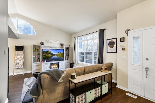 living room featuring lofted ceiling, a wealth of natural light, and dark hardwood / wood-style flooring