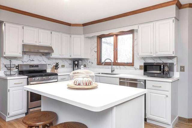 kitchen with a breakfast bar, sink, appliances with stainless steel finishes, a kitchen island, and white cabinets