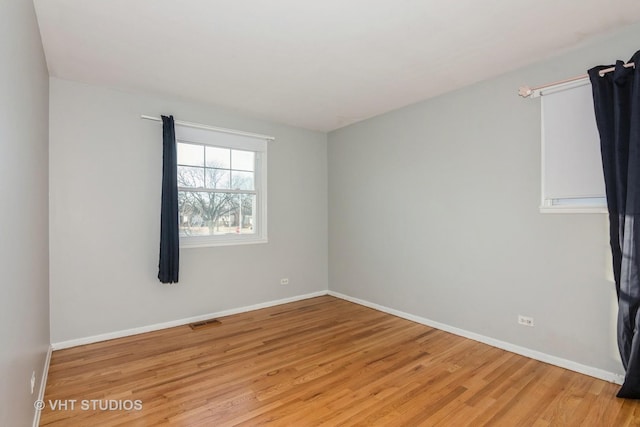 unfurnished room with light wood-type flooring, baseboards, and visible vents