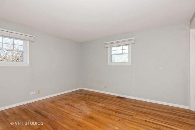 unfurnished room with baseboards, visible vents, and wood finished floors