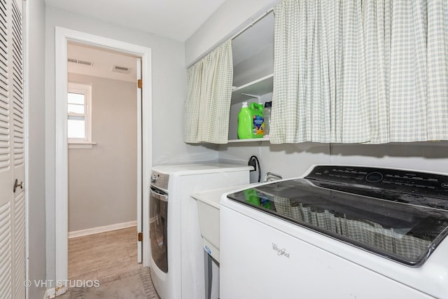 laundry area featuring laundry area, visible vents, light wood-style flooring, and separate washer and dryer