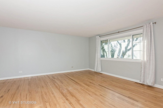 empty room with light wood-style flooring, visible vents, and baseboards