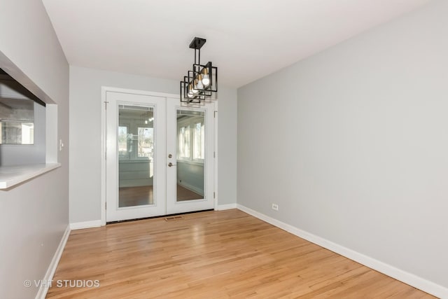 unfurnished dining area with baseboards, a chandelier, visible vents, and light wood-style floors