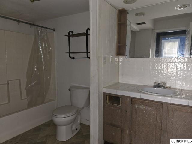 full bathroom featuring vanity, shower / tub combo, and toilet