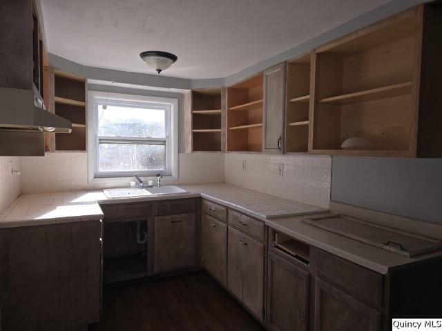 kitchen featuring sink, backsplash, dark hardwood / wood-style flooring, tile countertops, and exhaust hood