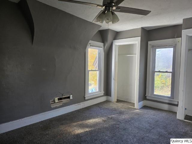 unfurnished bedroom with multiple windows, carpet floors, and ceiling fan