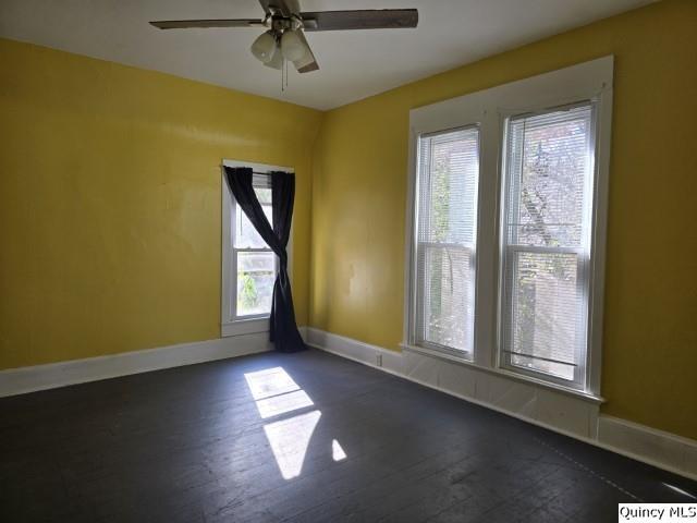 unfurnished room featuring dark wood-type flooring and ceiling fan