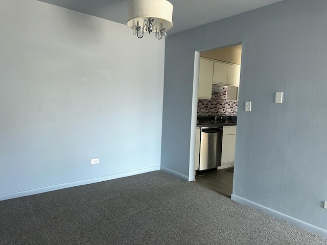 unfurnished dining area featuring a sink, dark carpet, baseboards, and an inviting chandelier