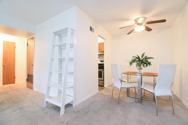 carpeted dining space with ceiling fan