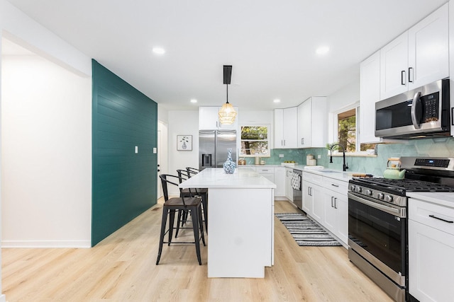 kitchen with hanging light fixtures, a kitchen island, white cabinets, and appliances with stainless steel finishes