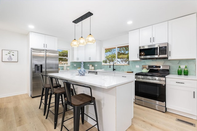 kitchen featuring stainless steel appliances, white cabinetry, a kitchen island, and a kitchen breakfast bar