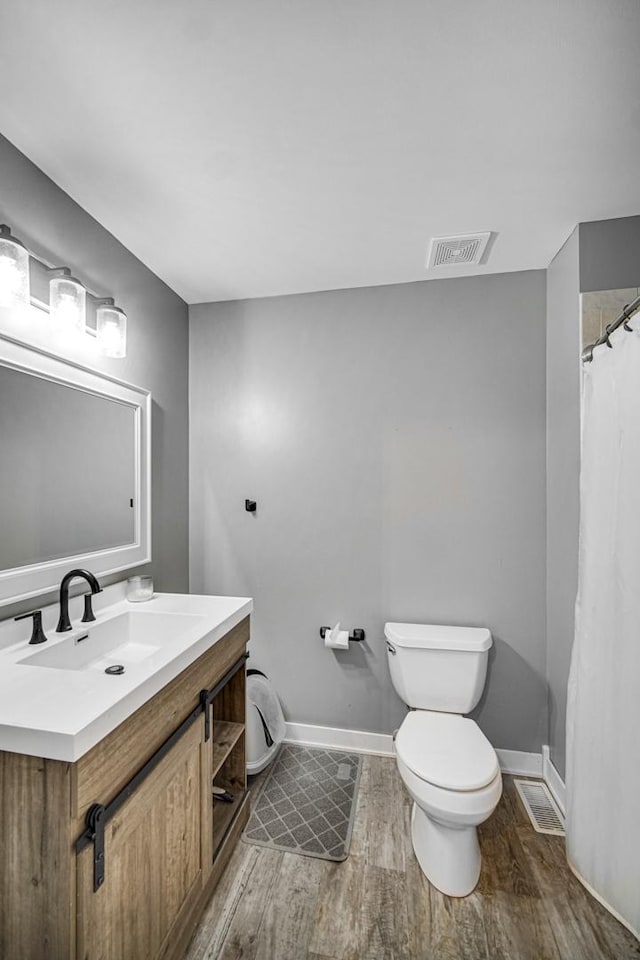 bathroom featuring vanity, hardwood / wood-style flooring, and toilet