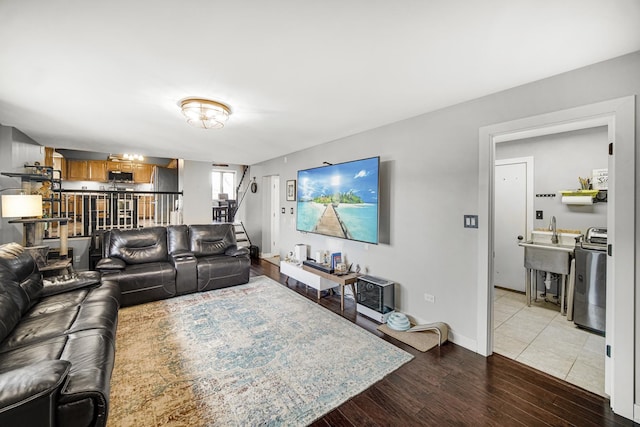 living room featuring washer / clothes dryer, sink, and light hardwood / wood-style floors