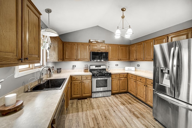 kitchen with stainless steel appliances, sink, light wood-type flooring, and decorative light fixtures