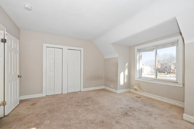 bonus room with light colored carpet and vaulted ceiling