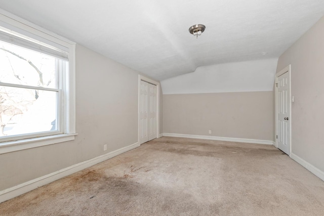 unfurnished room with vaulted ceiling and light carpet