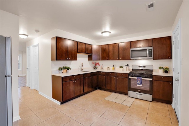 kitchen featuring sink, dark brown cabinets, stainless steel appliances, and light tile patterned flooring