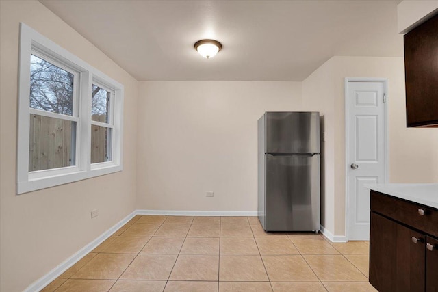 kitchen featuring light tile patterned floors, dark brown cabinets, and stainless steel refrigerator