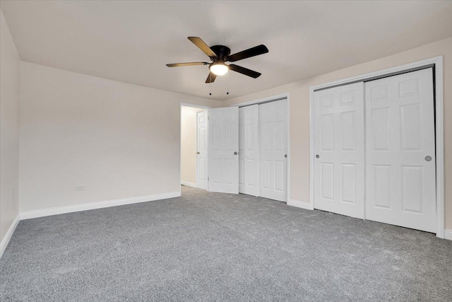 unfurnished bedroom with carpet flooring, two closets, and ceiling fan