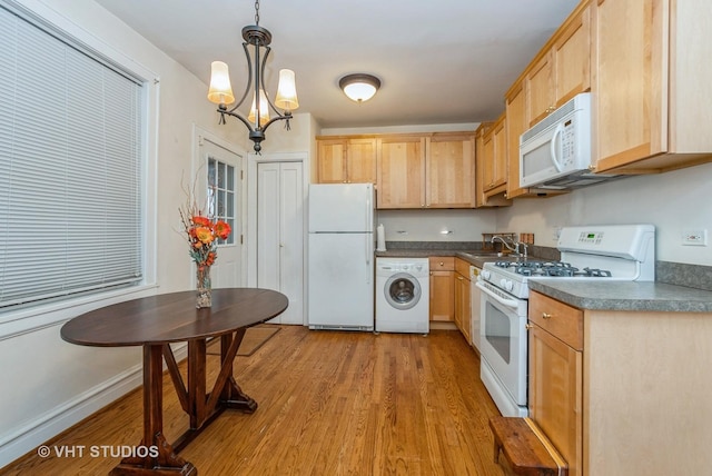 kitchen featuring washer / clothes dryer, dark countertops, white appliances, and a sink