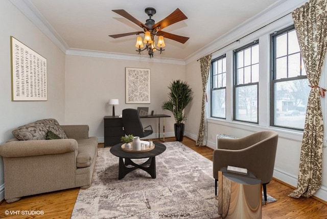 sitting room featuring light wood-style floors, baseboards, ornamental molding, and a ceiling fan