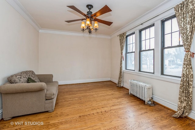 sitting room featuring ornamental molding, baseboards, light wood-style flooring, and radiator heating unit