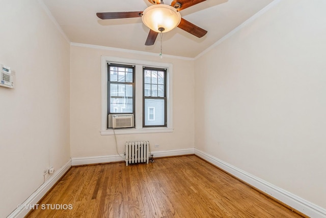 empty room with baseboards, crown molding, radiator heating unit, and wood finished floors